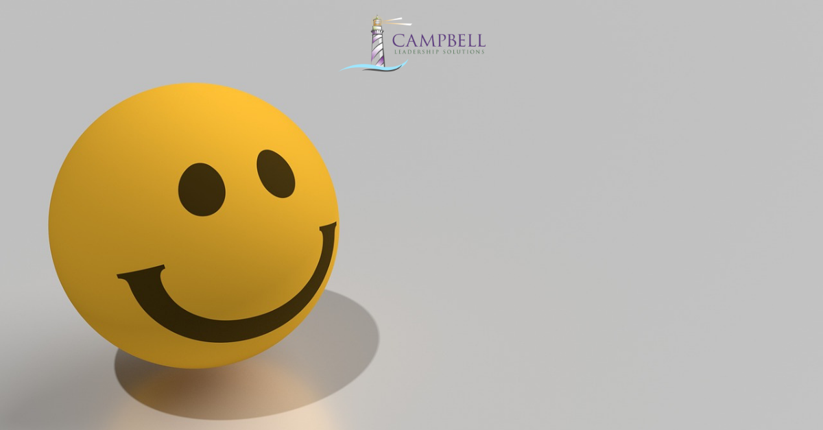 A yellow stress ball with a smiley face. Campbell Leadership Solutions